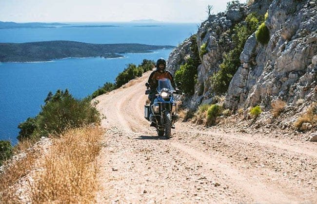 Beginner rider receiving instruction during an off-road motorcycle training session in Italy's countryside terrain