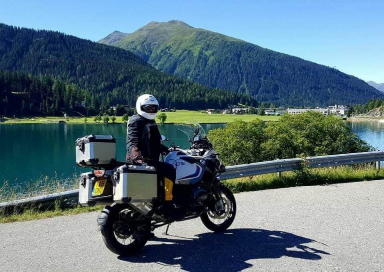 Biker customizing a motorcycle tour route on a map with scenic Italian landscapes in the background