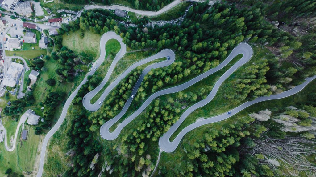 Motorcyclists ascend a winding mountain road with the breathtaking Dolomite peaks in the background, highlighting the thrill of the Dolomite motorcycle tour.