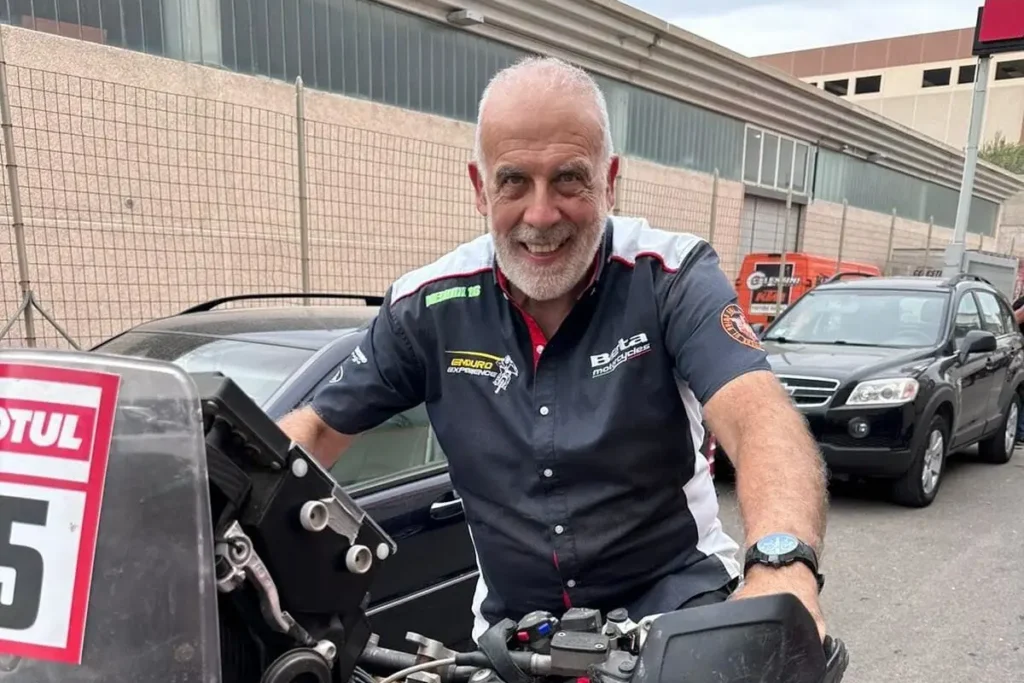 Mario Menicocci, experienced enduro instructor at Italy Moto Tours, smiling beside a rally bike during a tour event in Italy.