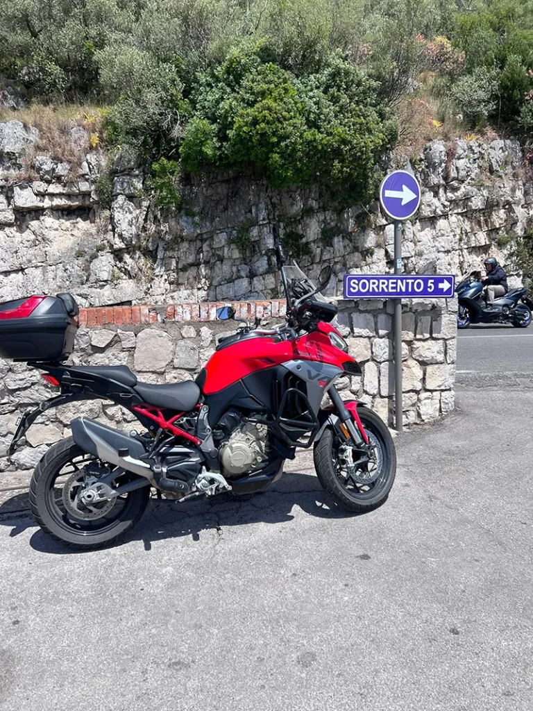 Italy Moto Tours Red Ducati parked by a road sign pointing to Sorrento, Italy during an Italy Moto Tours scenic ride along the Amalfi Coast region