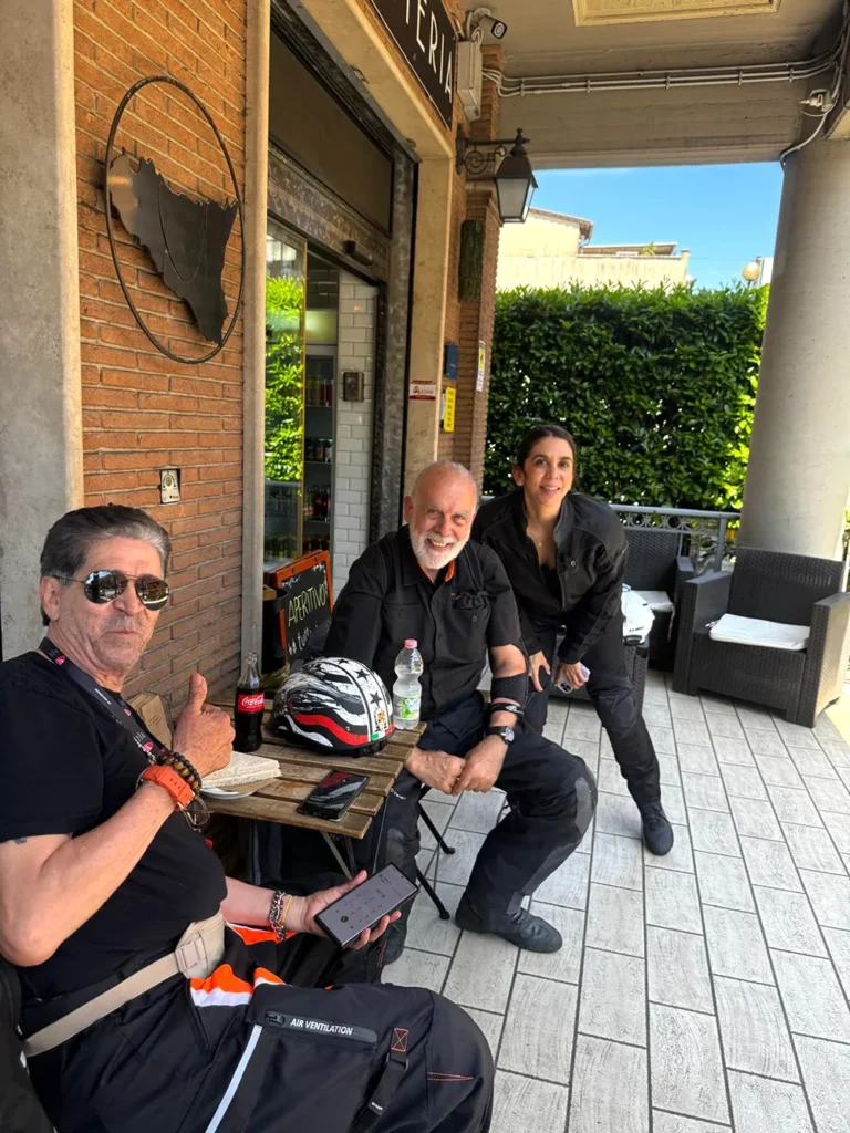 Italy Moto Tours Happy tour members and instructor relaxing outside a café during a guided Italy Moto Tours motorcycle adventure in Italy