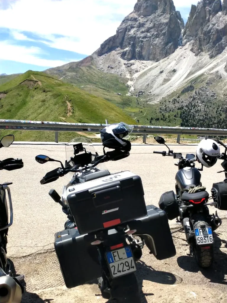Parked touring motorcycles with helmets near rugged Dolomites peaks at a mountain-pass viewpoint