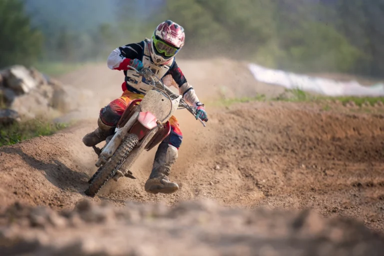 Italy Moto Tours Dirt bike leans into a muddy track corner, spraying dirt into the air on a race circuit