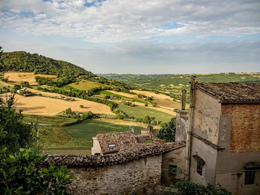 Italy Moto Tours Stone houses overlooking patchwork fields and green hills in the Marche region of central Italy