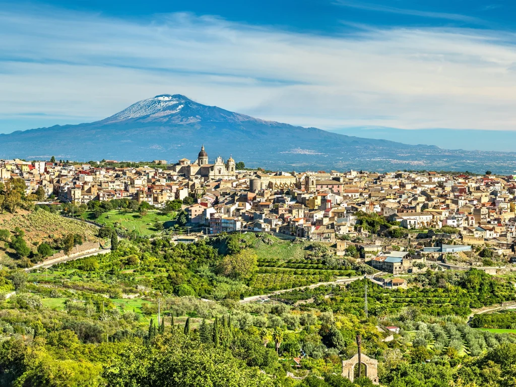 Italy Moto Tours Mount Etna rising behind a Sicilian hill town with vineyards and terraces in the foreground, Sicily, Italy.