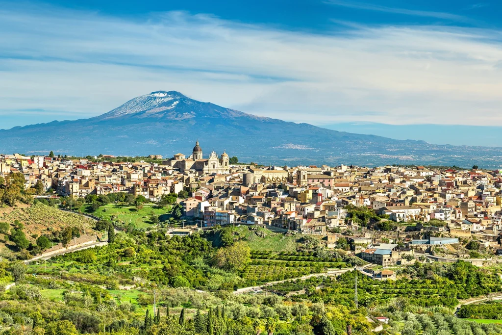 Italy Moto Tours Mount Etna rising behind a Sicilian hill town with vineyards and terraces in the foreground, Sicily, Italy.