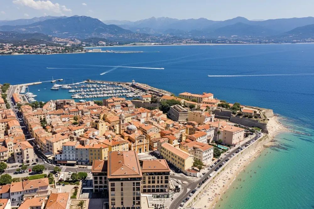 Italy Moto Tours Aerial view of Ajaccio’s bay, marina and sandy beach backed by mountains on Corsica