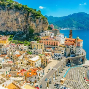 Aerial view of Atrani on the Amalfi Coast—pastel houses under cliffs, seaside church, and turquoise bay