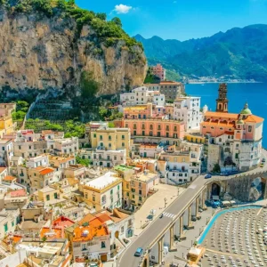 Aerial view of Atrani on the Amalfi Coast—pastel houses under cliffs, seaside church, and turquoise bay