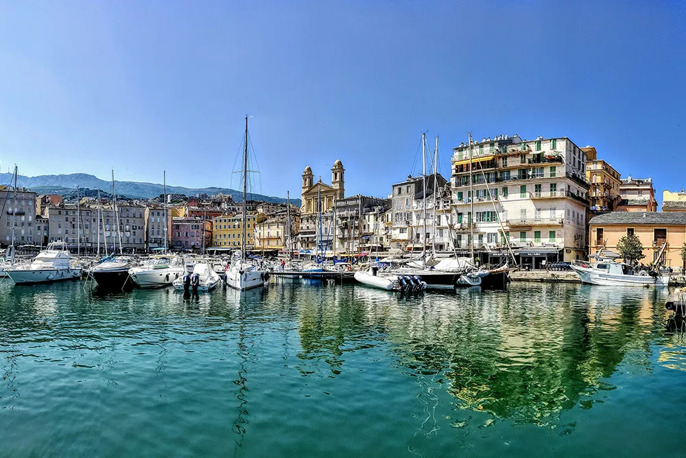 Italy Moto Tours Boats moored in the Old Port of Bastia with colorful waterfront buildings on Corsica, France