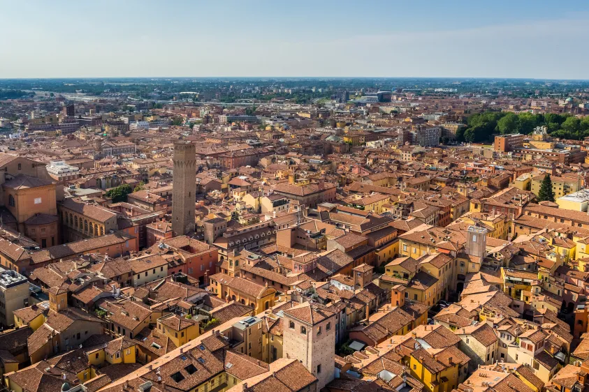 Italy Moto Tours Aerial panorama of Bologna’s historic center with terracotta rooftops and the medieval Asinelli and Garisenda towers.