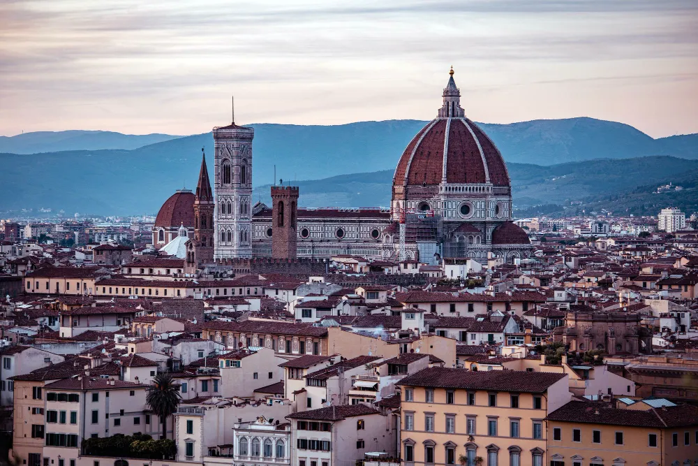 Italy Moto Tours Panoramic view of Florence with the Duomo’s red dome and Giotto’s bell tower rising above the historic city center.