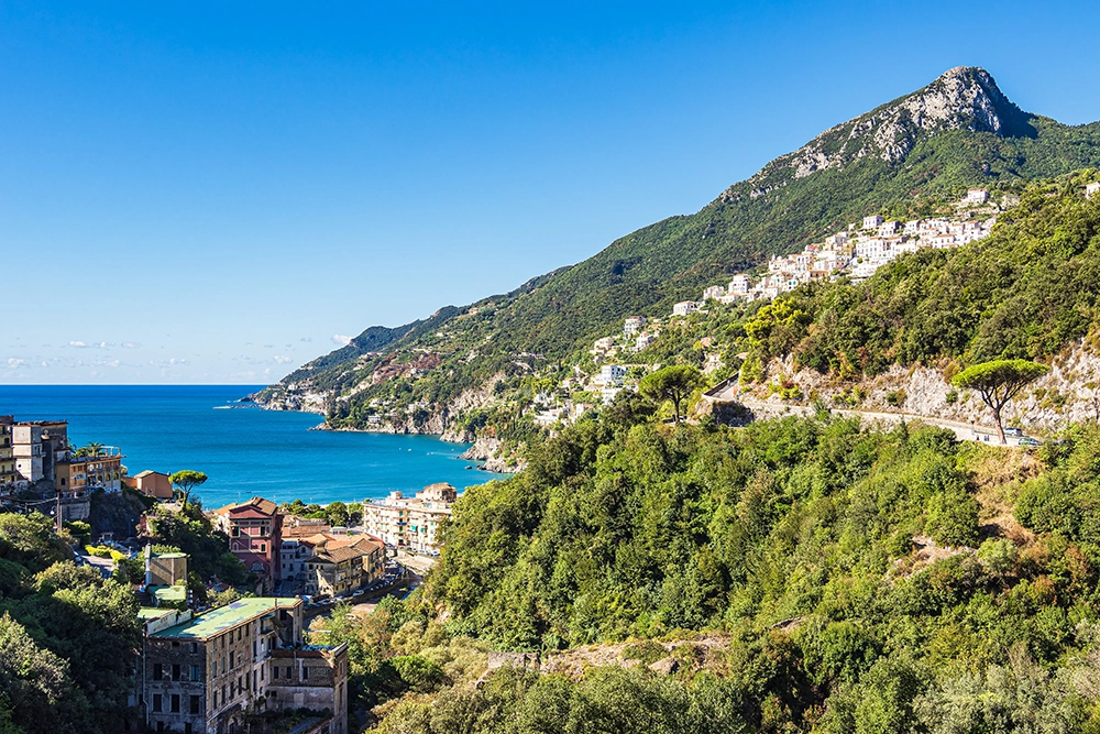 Italy Moto Tours Panoramic view of Vietri sul Mare on the Amalfi Coast, with hillside houses, the SS163 coastal road and the Tyrrhenian Sea below.