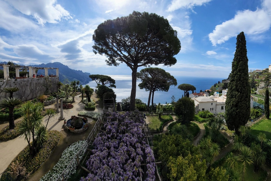 Italy Moto Tours Panoramic view of the terraced gardens at Villa Rufolo in Ravello with umbrella pines, flowers and the Tyrrhenian Sea beyond.