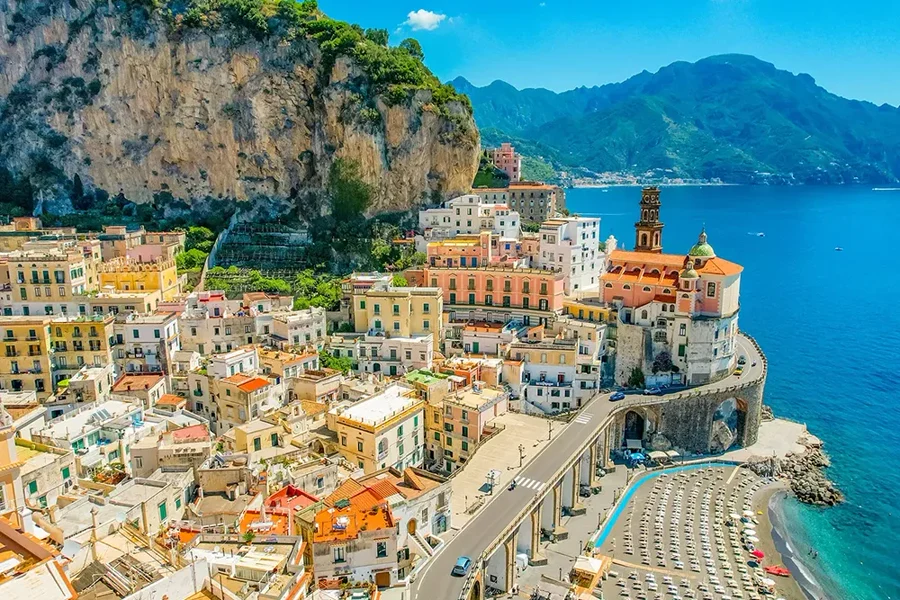 Aerial view of Atrani on the Amalfi Coast—pastel houses under cliffs, seaside church, and turquoise bay