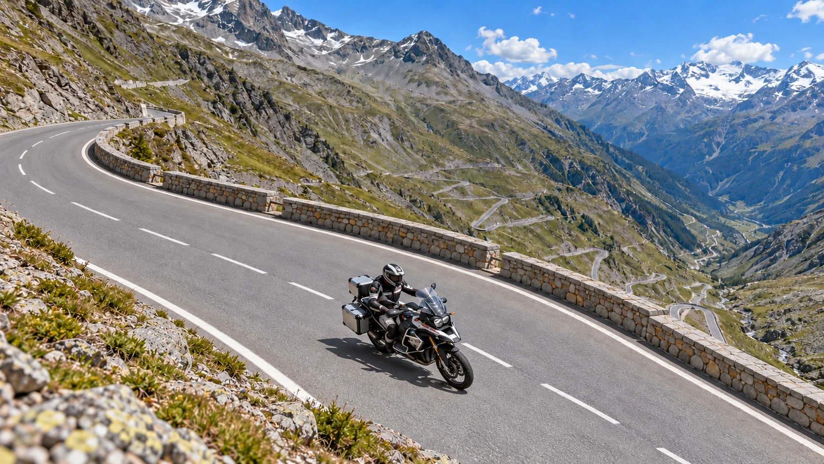 Touring motorcyclist rounding a mountain hairpin above a series of Alpine switchbacks.