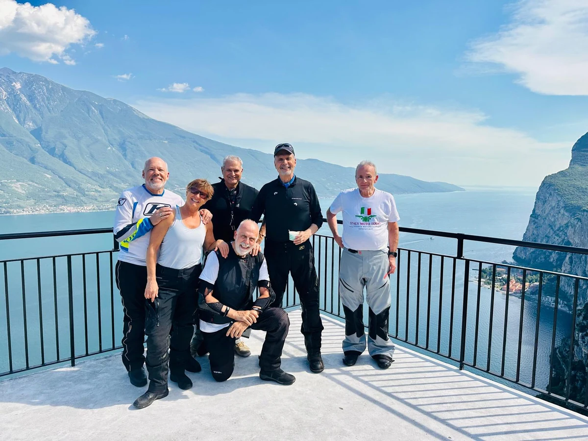 A group of motorcycle tour participants at a scenic mountain viewpoint.